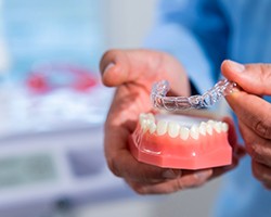 Dentist placing clear aligner over sample teeth